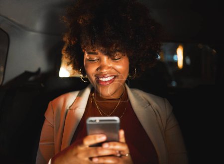 Foto de Mujer negra, afro y teléfono por la noche en taxi, viajes o comunicación en redes sociales o redes sociales. Sonrisa femenina africana feliz en el chat en línea o tarde en la noche en el teléfono inteligente móvil en el coche. - Imagen libre de derechos