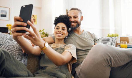 Photo for Interracial couple, selfie and happy on couch, relax at home with social media, streaming and memory with commitment. Smile in picture, post and love, care and trust, people in lounge with romance. - Royalty Free Image