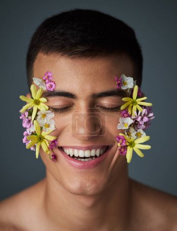 Photo for Face, happy man and flowers, beauty and natural, cosmetics and art deco isolated on studio background. Nature aesthetic, smile in portrait and dermatology, eco friendly skincare and clean with spring. - Royalty Free Image