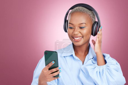 Photo for Music, headphones and black woman with phone in studio for streaming, radio or listen on pink background. Smartphone, app and African lady model with online audio, podcast and earphones for album. - Royalty Free Image