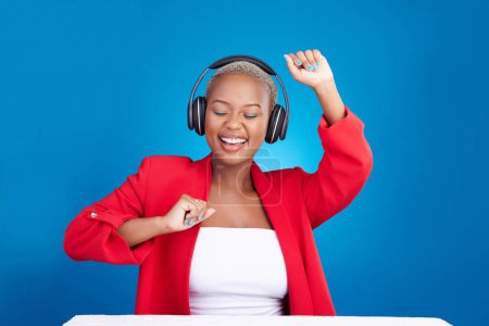 Téléchargez les photos : Musique, danse et femme noire avec écouteurs dans la célébration du studio avec des nouvelles, des commentaires ou de la promo sur fond bleu. Liberté, dame heureuse et africaine dansant sur écouteurs radio, podcast ou streaming. - en image libre de droit