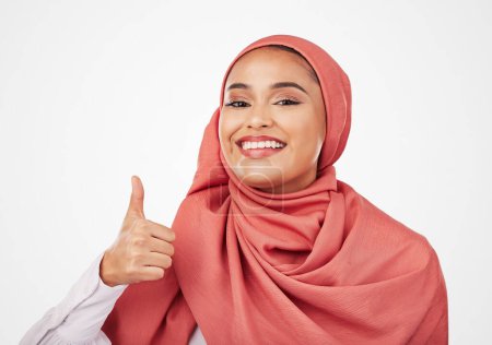 Foto de Mujer musulmana, retrato y pulgares hacia arriba con hijab en agradecimiento, éxito o ganar contra un fondo de estudio. Persona femenina feliz, islam y bufanda con emoji como, sí signo o OK en la aprobación elegante. - Imagen libre de derechos