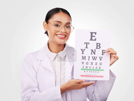 Photo for Woman, portrait and chart in eye exam, letter or vision of optometrist in healthcare or sight against a studio background. Happy doctor smile with glasses in optometry assessment, diagnosis or test. - Royalty Free Image