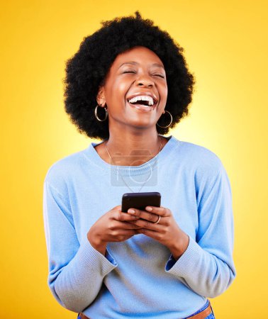Woman, laugh and typing on smartphone in studio, reading funny social media post and mobile news on yellow background. Happy african model, cellphone and joke of meme, multimedia notification or tech.