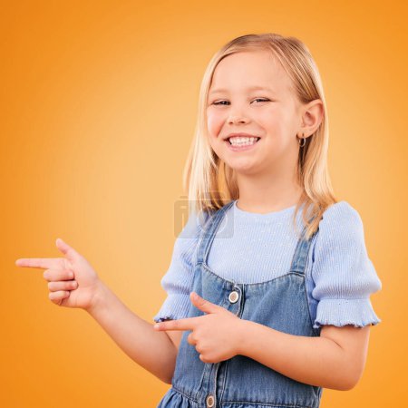 Photo for Happy, portrait and child with finger gun in studio for advertising announcement or promotion. Young girl kid on orange background for pointing or hand sign for direction, attention or excited smile. - Royalty Free Image
