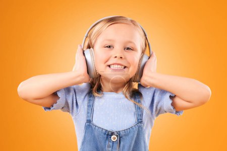 Photo for Headphones, portrait or child streaming music to relax with freedom in studio on orange background. Face, smile or happy girl listening to a fun radio song, sound or audio on an online subscription. - Royalty Free Image