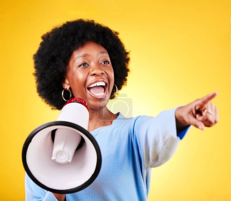 Photo for Happy woman, loudspeaker or megaphone and pointing in studio for voice or announcement. African person with speaker for broadcast message, breaking news or speech communication on yellow background. - Royalty Free Image