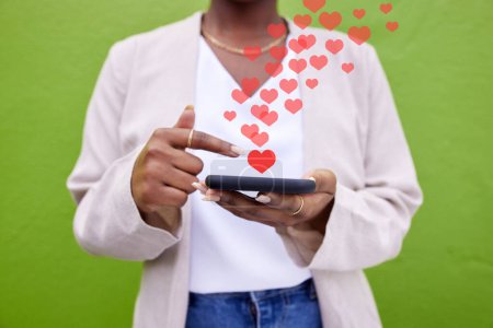 Photo for Phone, hands and woman with heart icon for online media, social network or feedback on mobile app. Smartphone, closeup and user typing post, communication and love sign emoji on green background wall. - Royalty Free Image