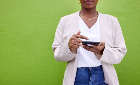 Photo for Hands, internet and phone for communication by a wall or green background for connection. Closeup of a woman with a smartphone for social media search, networking and mobile app chat or mockup space. - Royalty Free Image