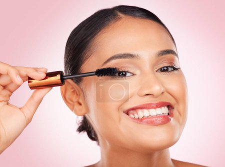Photo for Portrait, makeup and a woman with mascara on a pink background for eyelash beauty in studio. Smile, young and a female model marketing a cosmetics product for facial glow, skincare or wellness. - Royalty Free Image