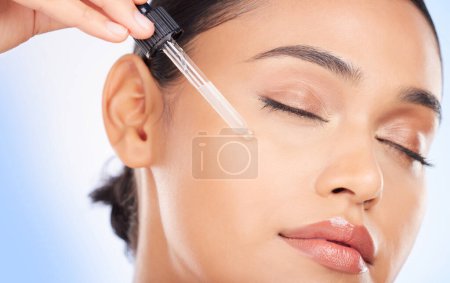 Photo for Essential oil, facial and woman in studio for skincare, wellness or hydration serum application on blue background. Hyaluronic acid, vitamin c or retinol for lady face, collagen or cosmetic treatment. - Royalty Free Image