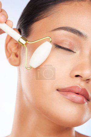 Photo for Woman, face roller and massage in studio for skincare, grooming and aesthetic dermatology on white background. Model, crystal cosmetics and facial beauty tools for lymphatic drainage, shine and glow. - Royalty Free Image