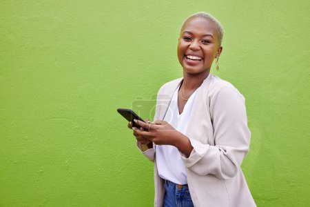 Foto de Mujer negra, sonrisa y teléfono para retrato por una pared o fondo verde con internet. Mujer africana riendo con smartphone para redes sociales, networking y comunicación o chat. - Imagen libre de derechos