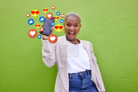 Photo for Portrait, excited black woman and phone emojis, social media icons and thumbs up notification. Smartphone communication, like opinion vote and African user show feedback on green background wall. - Royalty Free Image