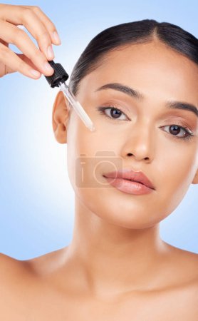 Photo for Woman, face and oil serum, beauty and skincare with liquid collagen isolated on blue background. Natural cosmetics, wellness and portrait, dermatology with pipette and hyaluronic acid in a studio. - Royalty Free Image