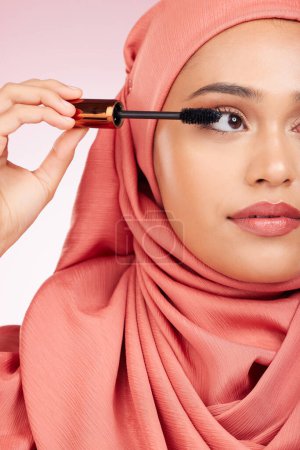 Photo for Beauty, luxury and mascara with a muslim woman closeup in studio on a pink background for cosmetics. Makeup, eyelash and brush with a young islamic model getting ready to apply cosmetics to her face. - Royalty Free Image