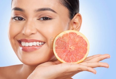 Photo for Portrait, beauty and grapefruit with a natural woman in studio on a blue background for health or wellness. Face, skincare and smile with a happy young model holding fruit for detox or antioxidants. - Royalty Free Image