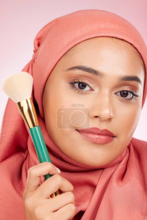 Téléchargez les photos : Maquillage, pinceau et portrait de femme musulmane avec le sourire des cosmétiques et le fard à joues en studio. Facial, lumineux et heureux femme avec la beauté, les soins de la peau et briller avec un hijab et la peau pour le visage. - en image libre de droit