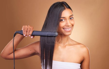 Photo for Straightener, hair care and woman portrait with smile and happy from Brazilian treatment in studio. Salon, natural beauty and hairdresser tool for healthy hairstyle and wellness with brown background. - Royalty Free Image