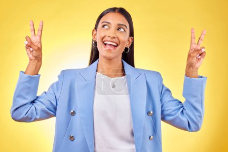 Foto de Moda, signo de paz y mujer india sobre fondo amarillo con sonrisa, actitud positiva y feliz. Emoji, negocio y persona en estudio para gesto de mano en ropa de moda, estilo profesional y traje. - Imagen libre de derechos