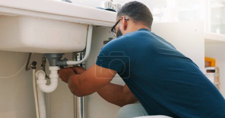 Photo for Plumber black man, kitchen and sink maintenance with tools, focus and pipe repair for drainage in home. Entrepreneur handyman, plumbing expert or small business owner in house for fixing water system. - Royalty Free Image