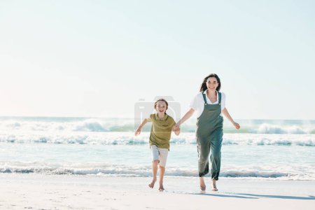 Foto de Correr, tomarse de la mano y la madre con el niño en la playa para la energía, la libertad y la maqueta de vacaciones de verano. El amor, el relax y la aventura con la familia en vacaciones junto al mar para la salud, la unión y los juegos juntos. - Imagen libre de derechos