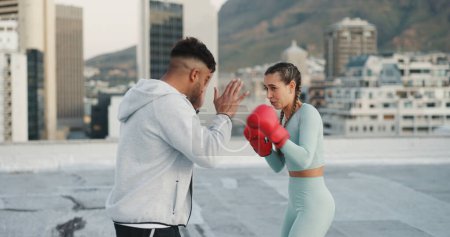 Photo for Fitness, personal trainer and boxing training on rooftop in city for exercise, sport or outdoor workout. Woman boxer and man coaching in sports practice for fighting, cardio or self defense in town. - Royalty Free Image
