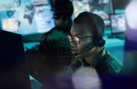 Military control room, computer and man with headset, support or tech for communication. Security, surveillance and soldier at help desk in army office at government cyber intelligence command center.