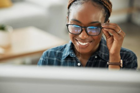 Photo for Face, smile and computer with a black woman in glasses working closeup in her home for remote employment. Happy, website and desktop with a young employee at work on her small business startup. - Royalty Free Image