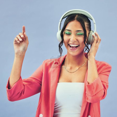 Photo for Music, headphones and happy woman dance in studio with podcast, track or audio subscription on blue background. Face, smile and lady model with freedom, energy or moving to radio or feel good podcast. - Royalty Free Image