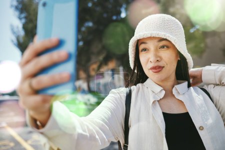 Photo for Woman on city street with selfie, travel blog and holiday memory for social media in streetwear. Influencer, streamer or gen z girl with urban fashion, photography or content creation with lens flare. - Royalty Free Image