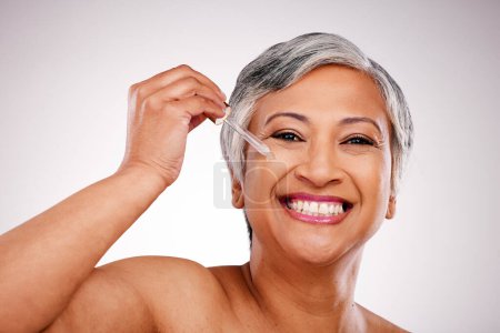 Photo for Beauty, portrait and mature happy woman with serum skin hydration, anti aging product or collagen oil for spa skincare treatment. Liquid dropper, hyaluronic acid and studio face on white background. - Royalty Free Image