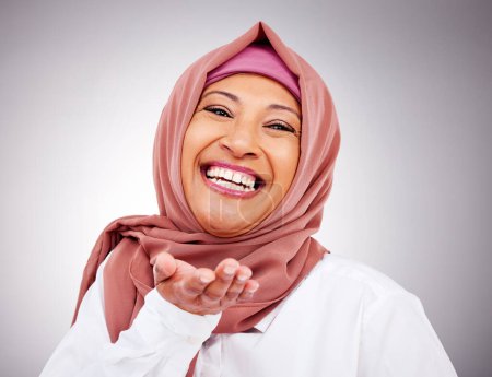 Foto de Golpe beso, feliz y retrato de mujer musulmana en estudio con maquillaje, cosméticos y belleza. Moda, estilo y rostro de persona islámica con gesto de mano por amor, afecto o emoji sobre fondo gris. - Imagen libre de derechos