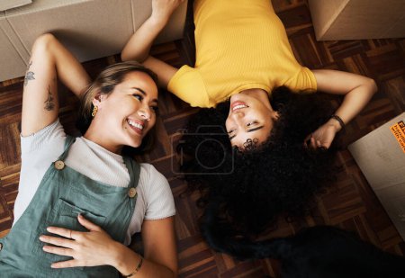 Photo for Top view, lesbian and couple with boxes, homeowners and achievement with love, bonding and property. Queer people, lgbtq or happy women on the ground, new apartment and conversation with real estate. - Royalty Free Image