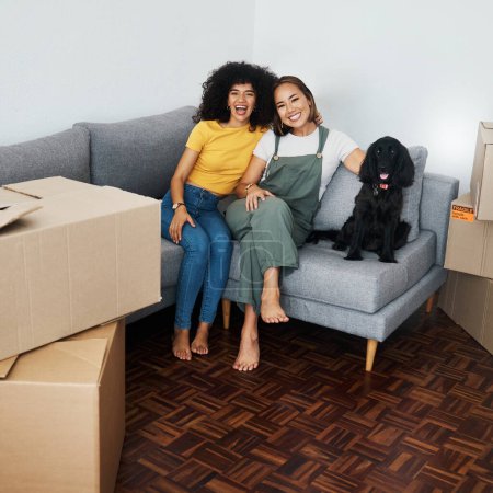 Dog, lesbian couple and new real estate, portrait and bonding together in living room. Happy gay women with pet in house on sofa, apartment and moving in to property home, laughing and funny animal.
