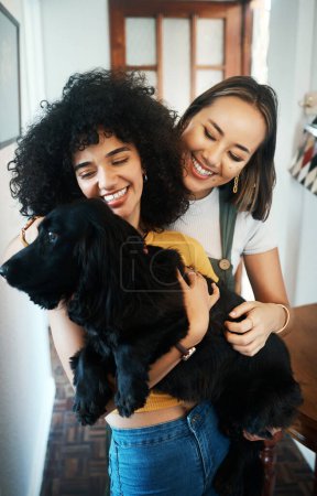 Photo for Happy, smile and lesbian couple holding dog in modern apartment for bonding together. Love, family and interracial young lgbtq women hugging and embracing their sweet animal pet puppy at home - Royalty Free Image