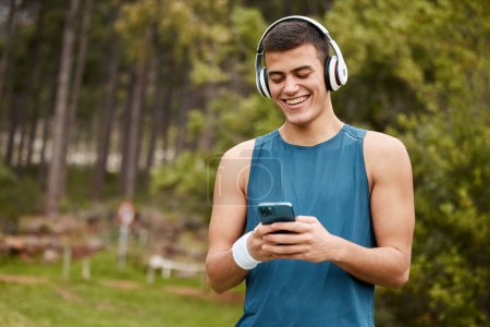 Photo for Fitness, headphones and a man outdoor with a phone listening to music with banner. Happy runner, athlete or sports person in nature park to start exercise, workout or training while streaming radio. - Royalty Free Image