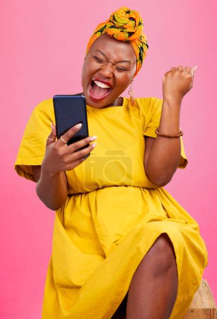 Téléchargez les photos : Célébration, gagnante et femme noire excitée pour app mobile affaire isolé en studio fond rose avec prix. Giveaway, Africain et heureux avec promotion, bonus et notification de la concurrence. - en image libre de droit