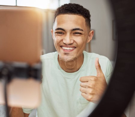 Photo for Phone, thumbs up and happy man in living room with social media, review or thank you. Ring light, smile and guy influencer online with feedback hand emoji, support or live streaming, blog or podcast. - Royalty Free Image