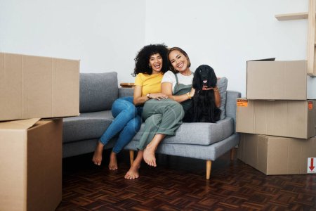 Photo for New home, portrait and lesbian couple with a dog on the sofa for moving boxes and relocation. Smile, lgbt and women or people on the living room couch of an apartment with a pet and a homeowner. - Royalty Free Image