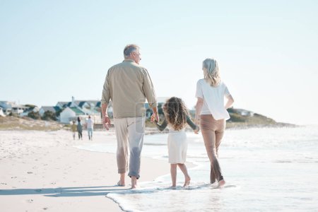 Photo for Relax, holding hands and grandparents with child at beach for travel, love and support. Summer vacation, care and retirement with family walking on seaside holiday for adventure, bonding and peace. - Royalty Free Image
