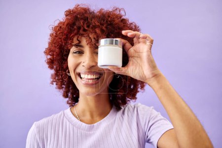 Photo for Portrait, beauty and cream for skincare with a woman holding a container in studio on a purple background. Face, smile and promotion of a product or serum for antiaging with a happy young model. - Royalty Free Image