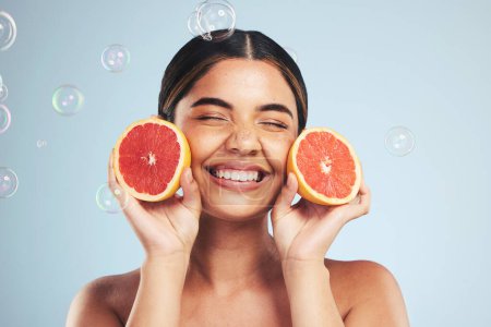 Photo for Smile, woman and grapefruit skincare in studio for natural, cosmetic or wellness on grey background. Beauty, happy and model face with citrus facial, fruit or vitamin c, collagen and bubble aesthetic. - Royalty Free Image