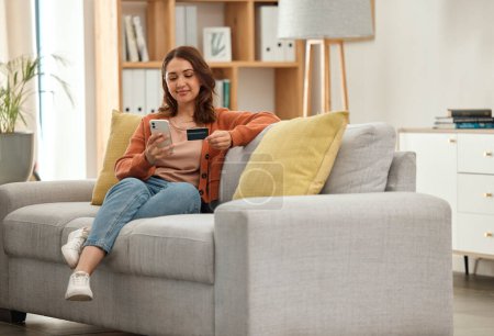 Home, woman and smartphone with credit card, ecommerce and online banking in a lounge. Person, savings or girl on a couch, cellphone and digital app with payment, finance and transaction with fintech.