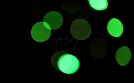 Foto de Verde, bokeh y luz en un estudio con un fondo oscuro para la celebración, evento o fiesta. Burla, brillo y color para resplandor, magia o brillo para la decoración festiva por un fondo negro con maqueta - Imagen libre de derechos