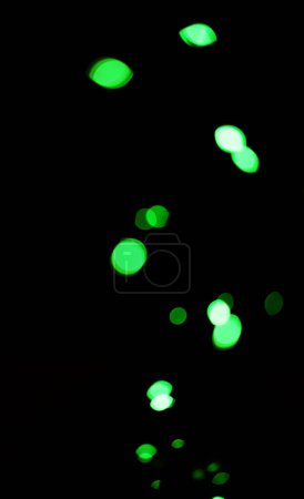 Téléchargez les photos : Bokeh, points verts et lumières sur fond noir avec motif, texture et maquette avec esthétique cosmique. Éclairage nocturne, particules scintillantes et lueur sur papier peint sombre avec espace, éclat de couleur et éclat. - en image libre de droit