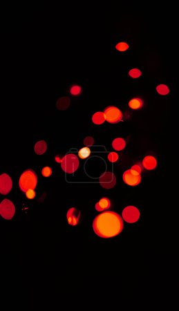 Foto de Luces bokeh, rojas y naranjas sobre fondo negro con patrón, textura y maqueta con estética cósmica. Iluminación nocturna, partículas de brillo y brillo en el fondo de pantalla oscuro con espacio, brillo de color y destello. - Imagen libre de derechos