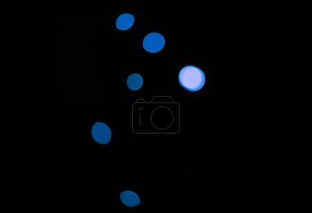 Téléchargez les photos : Bokeh, néon lumières bleues sur fond sombre et des points avec motif, texture et maquette avec esthétique cosmique. Éclairage nocturne, particules scintillantes et lueur sur papier peint noir avec espace, brillance et fusée éclairante - en image libre de droit