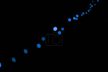 Téléchargez les photos : Bokeh, points bleu néon sur fond noir et lumières avec motif, texture et maquette avec esthétique cosmique. Éclairage nocturne, particules scintillantes et lueur sur papier peint sombre avec espace, brillance et fusée éclairante - en image libre de droit