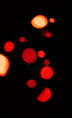 Foto de Luces Bokeh, rojas y anaranjadas sobre fondo oscuro con patrón, textura y maqueta con estética cósmica. Iluminación nocturna, partículas de brillo y brillo sobre fondo negro con espacio, brillo de color y destello. - Imagen libre de derechos